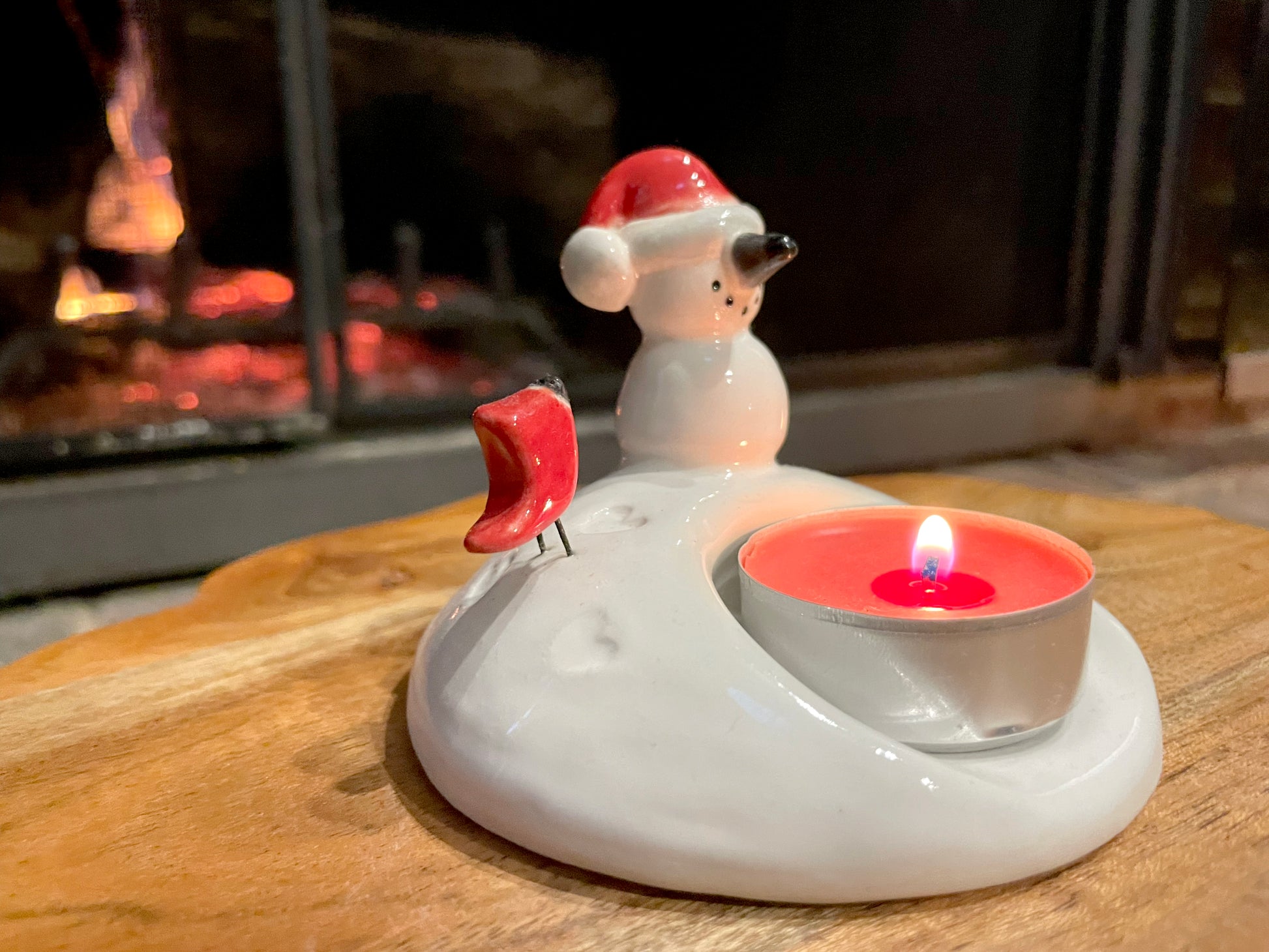 Tiny clay snowman and cardinal bird candle holder glowing with tea light.