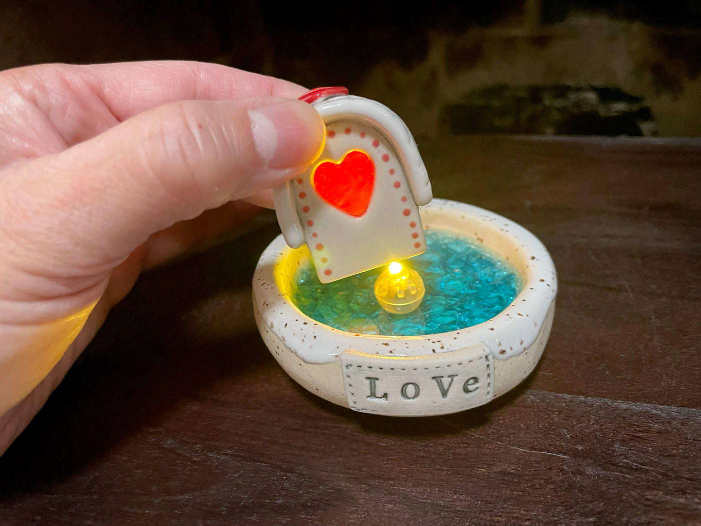Close-up of ceramic frozen lake incense burner with LED-lit mini cabin.