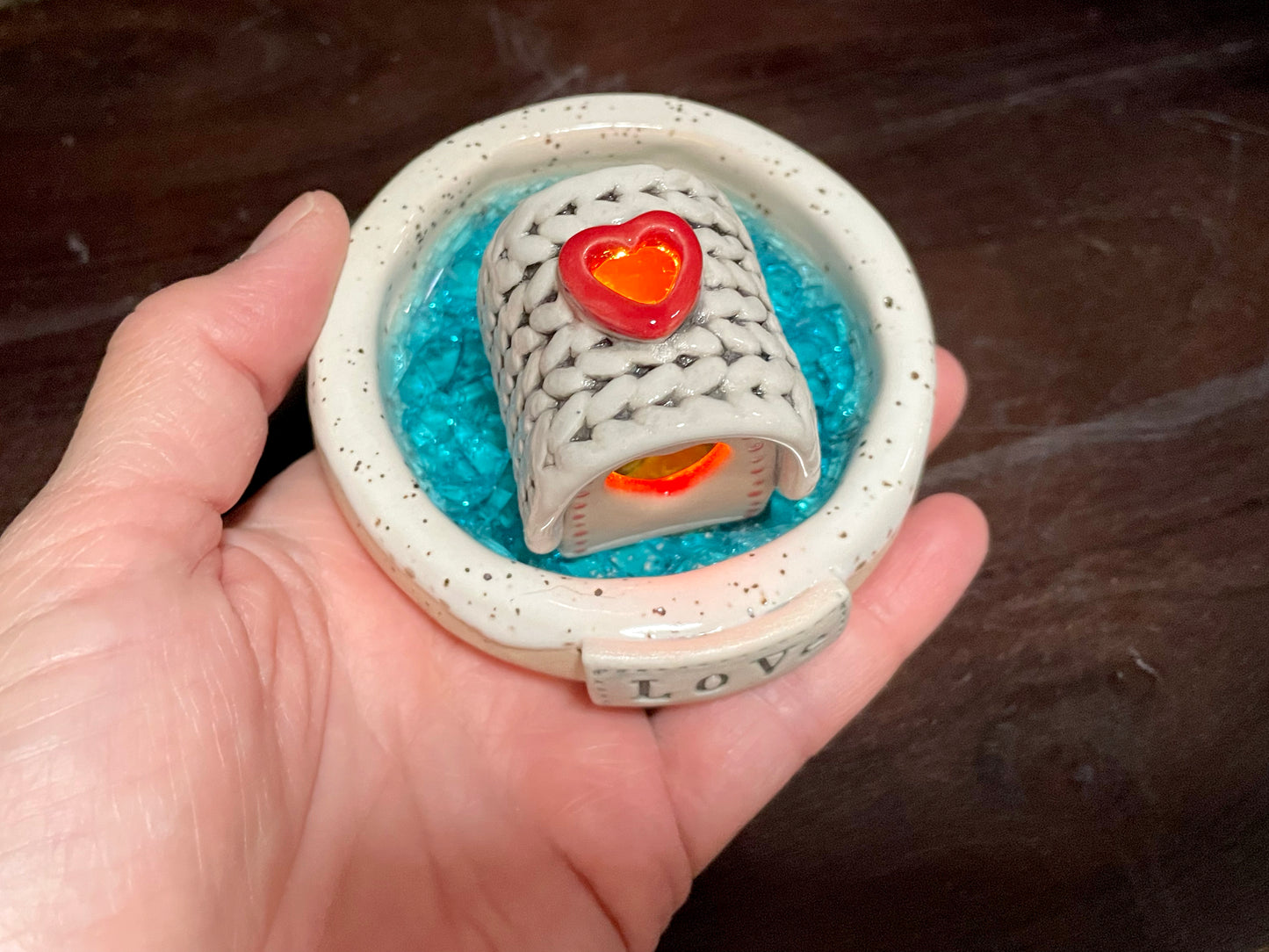 Close-up of ceramic frozen lake incense burner with LED-lit mini cabin.