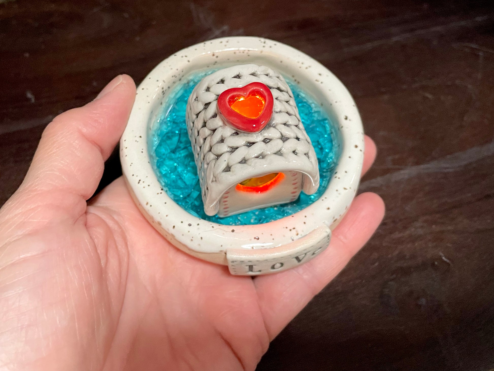 Close-up of ceramic frozen lake incense burner with LED-lit mini cabin.