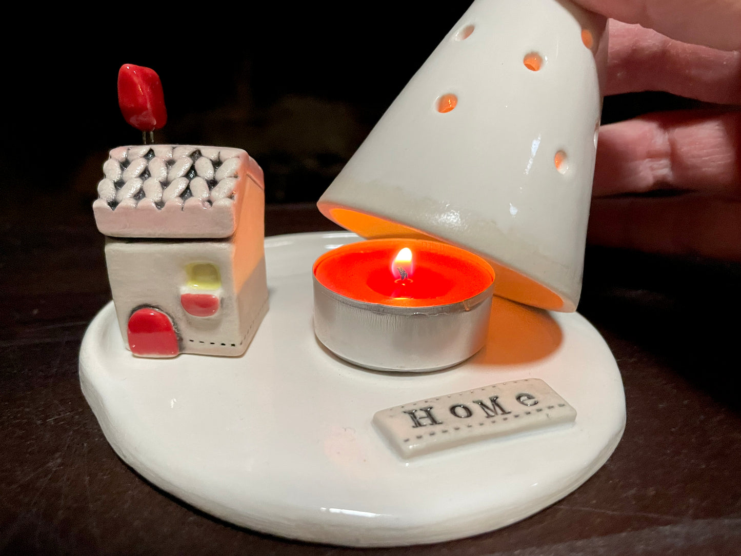 White ceramic warmer with a lit candle inside. Scandinavian-style Christmas decor featuring handmade ceramics cottage and tea light tree holder