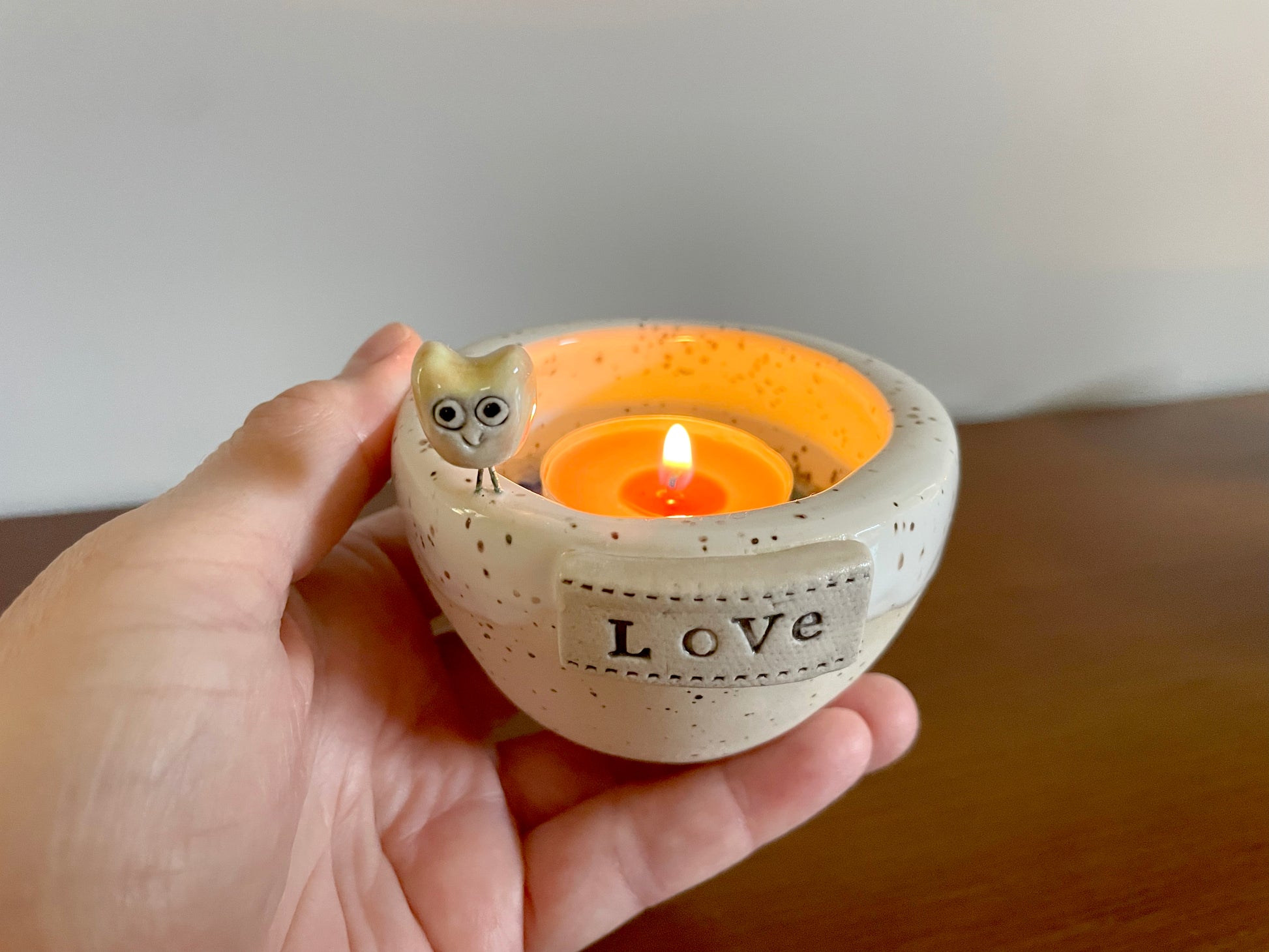 Ceramic candle holder with winter-inspired lake texture and shiny finish. Ceramic candle holder with a lit candle inside