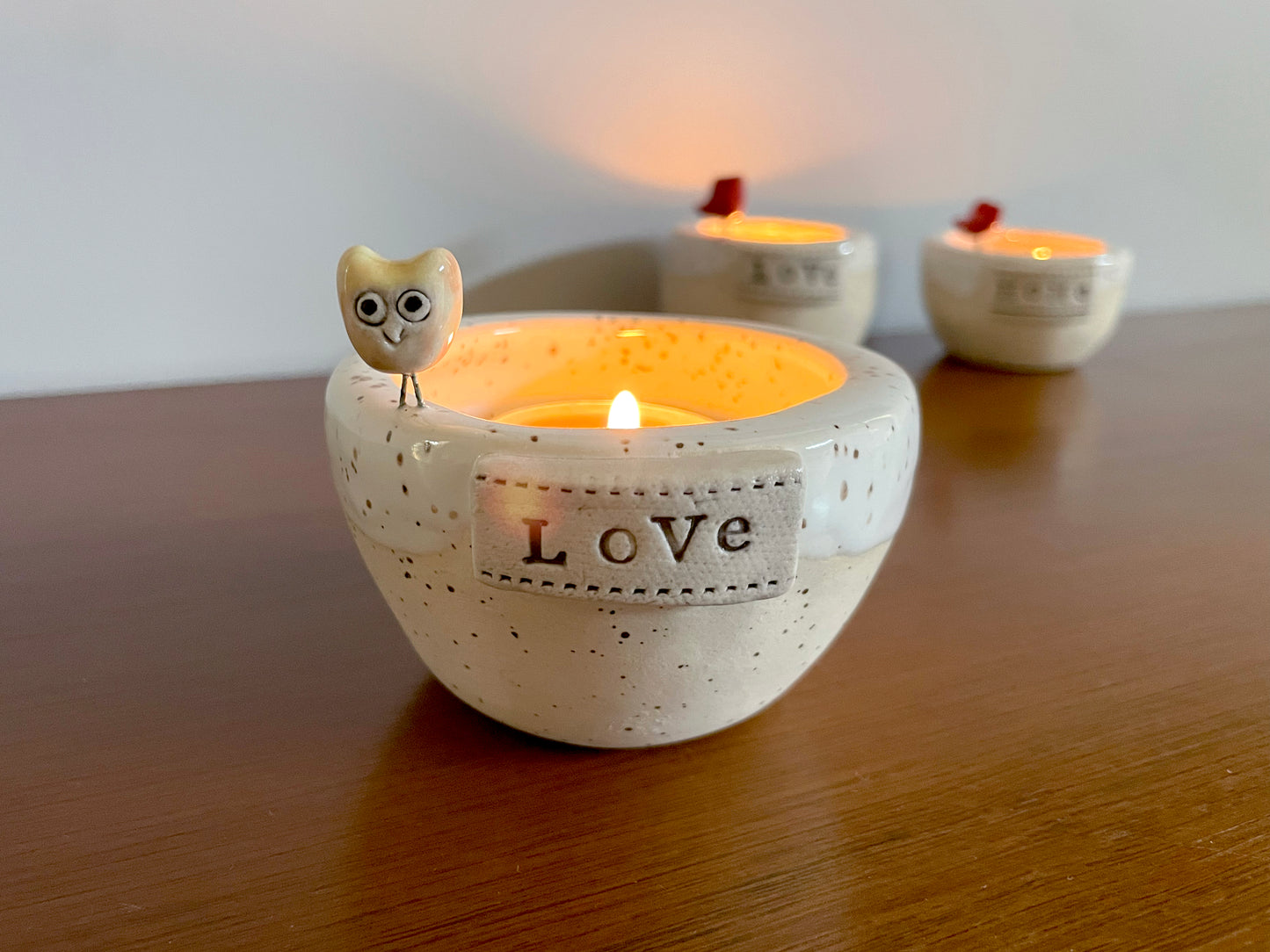 Ceramic candle holder with 'Love' text and owl design. Handmade white ceramic tea light holder with tiny owl perched on winter lake design.