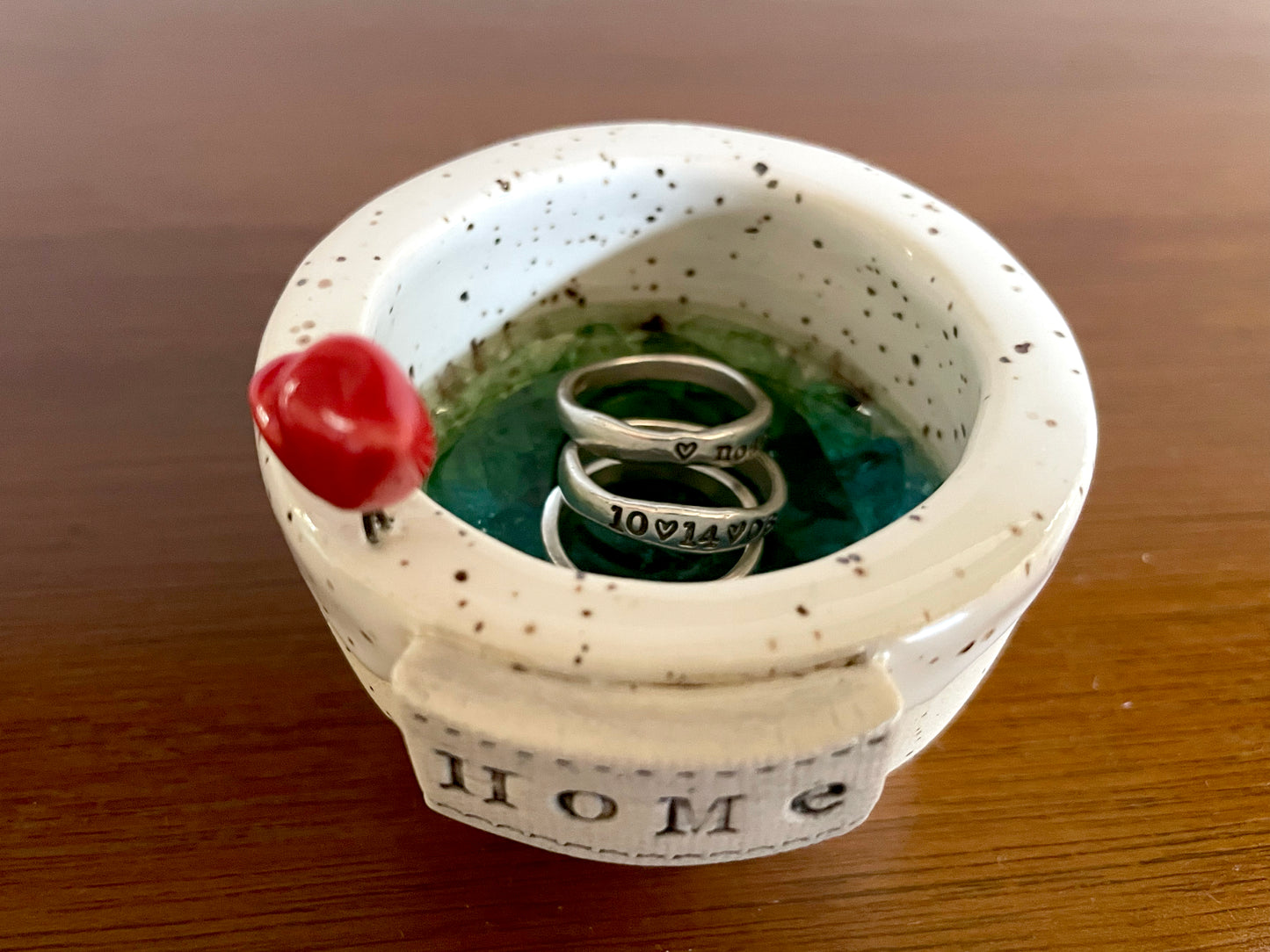 Handmade white clay dish with cardinal detail used as jewelry holder or home accent décor.. Ceramic pot with speckled design containing three rings.