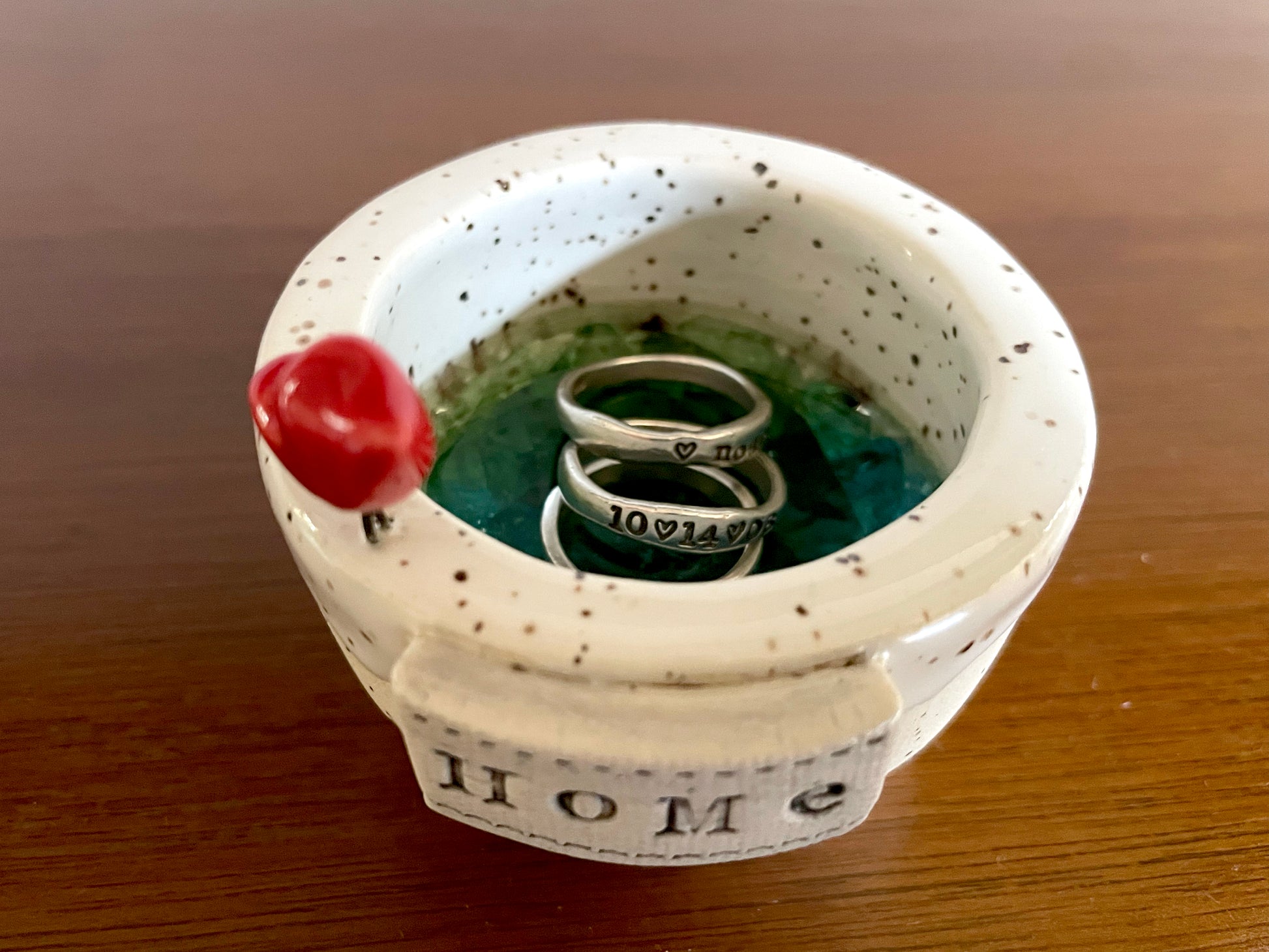 Handmade white clay dish with cardinal detail used as jewelry holder or home accent décor.. Ceramic pot with speckled design containing three rings.