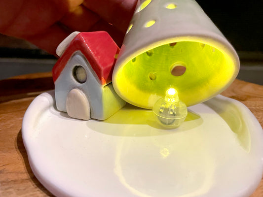 LED light glowing through ceramic mini village house and tree holiday decoration
