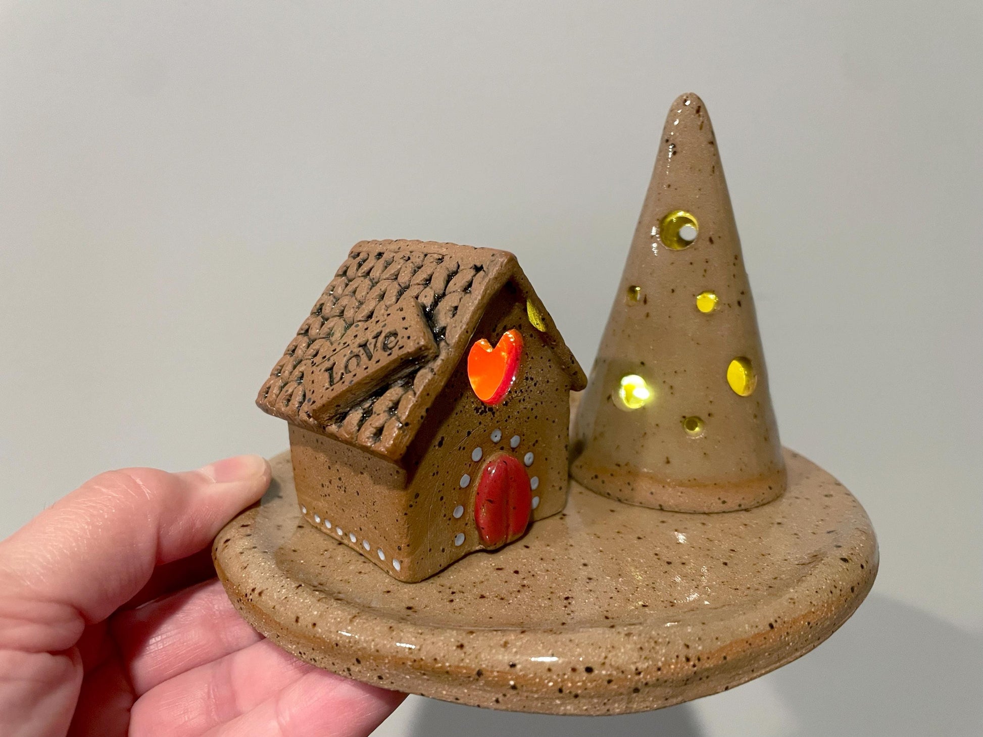 Ceramic house and cone with glowing eyes on a gray background