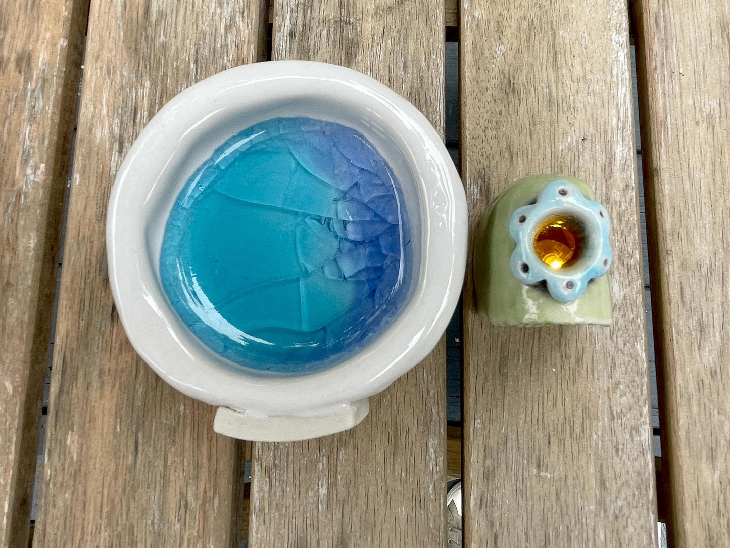 Blue glass object with cracked texture inside a white container on a wooden surface