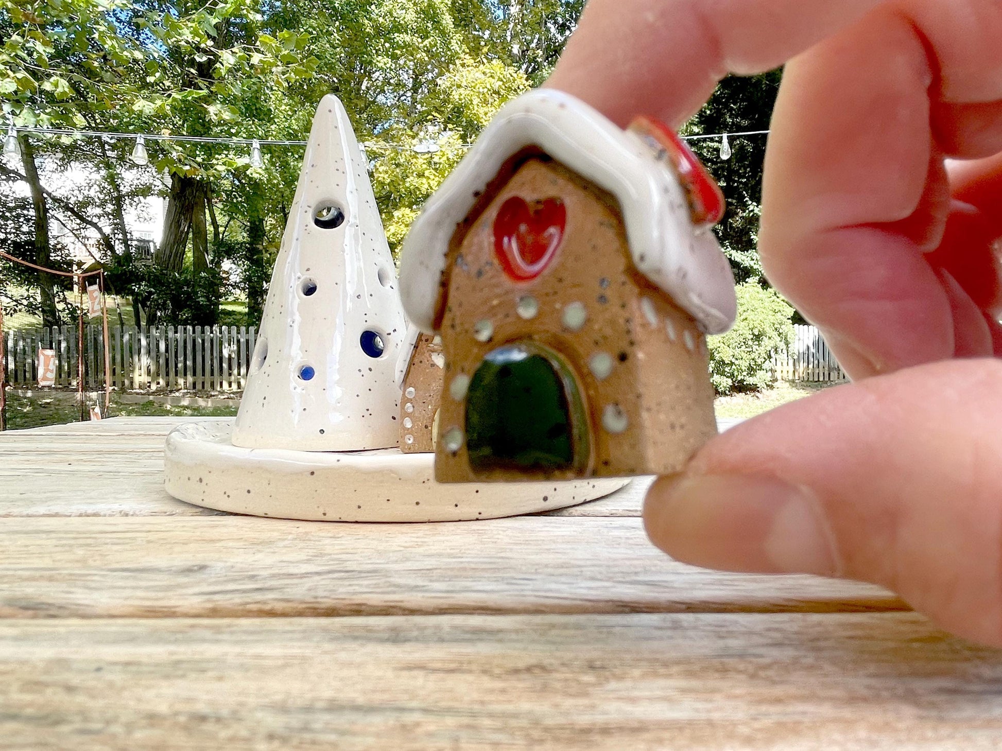 Small ceramic house with a heart on a wooden surface outdoors